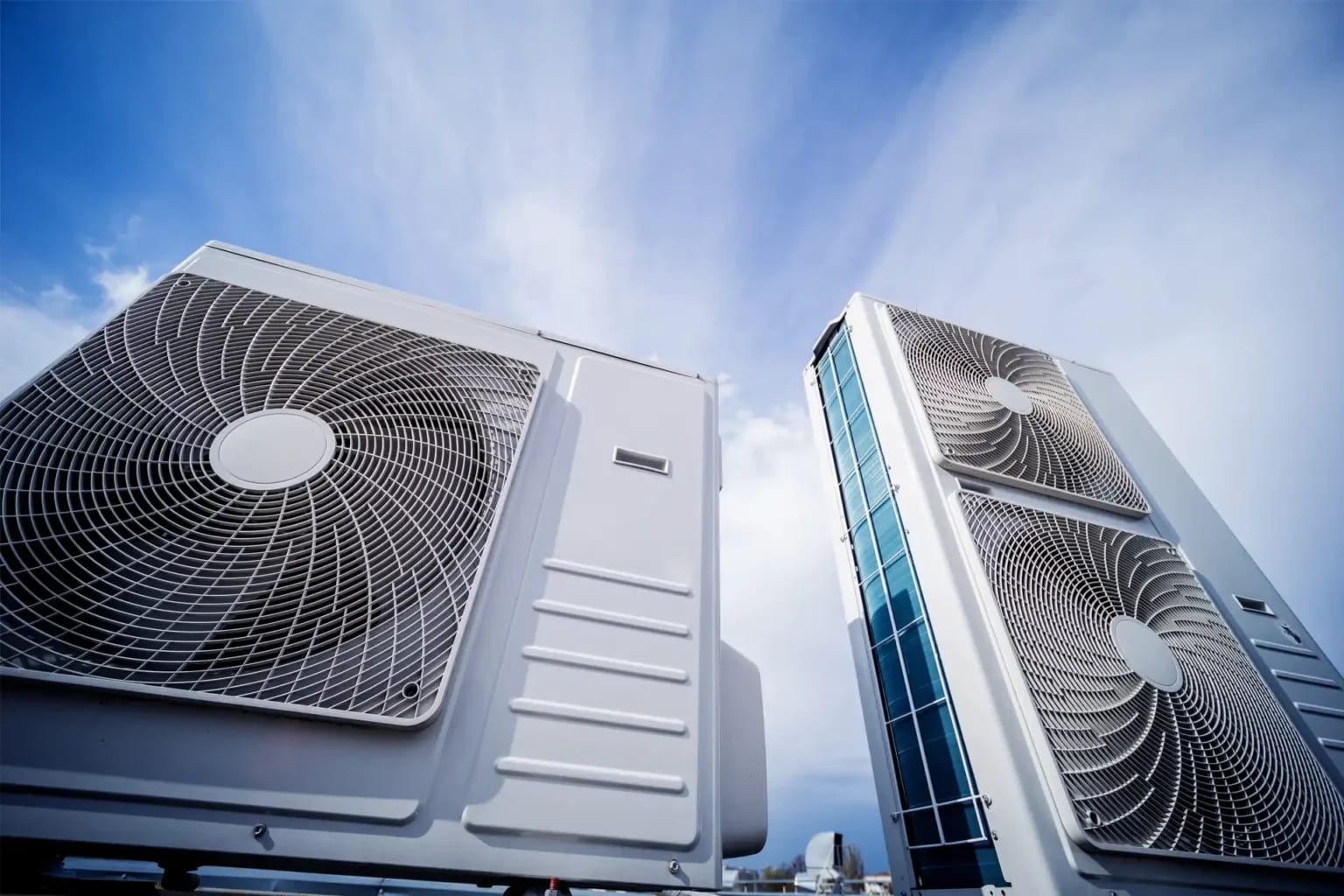 Two large-fan outdoor heat pump units mounted outside a building